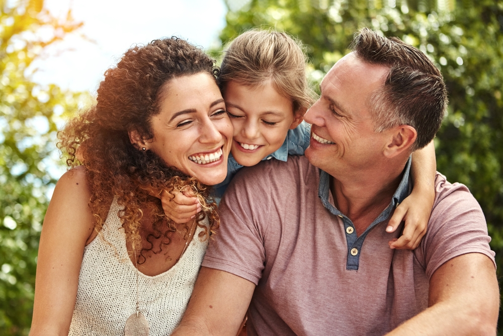 A joyful family embracing and smiling together outdoors, highlighting the benefits of family-friendly dental care and lifelong oral health - Menifee dentist.
