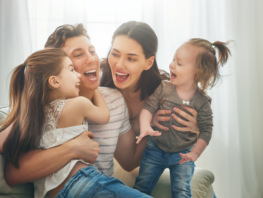 A joyful family with parents and children laughing together, representing the confidence and happiness that comes from maintaining healthy smiles through professional dental care - Dentist In San Jacinto, CA.