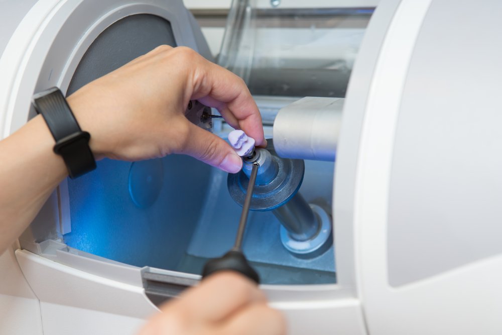 woman sets a workpiece in a dental milling machine for the manufacture of a dental crown